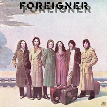 The self-titled debut album cover of the rock band Foreigner, featuring the six original members standing in long coats with suitcases, including the hit single Cold as Ice.