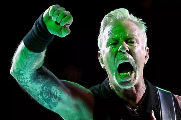 Lars Ulrich Powers Through Metallica Set in Black Stage Gear - Classic Rock Artists Lars Ulrich of Metallica in black attire, raising his fist mid-performance with fierce expression