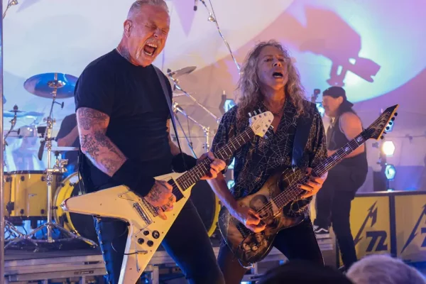 Metallica Hamptons Concert - James Hetfield and Kirk Hammett Live Performance - Classic Rock Artists James Hetfield and Kirk Hammett performing on stage with guitars during their intimate Metallica Hamptons concert at Stephen Talkhouse, with colorful stage lighting and drums visible in background.