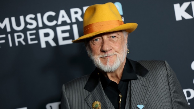 Mick Fleetwood Maui wildfires tribute, silver-bearded musician in yellow hat at charity event backdrop.