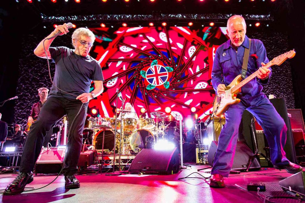 The Who performing live on stage during their North American Farewell Tour, with vibrant visuals behind them.