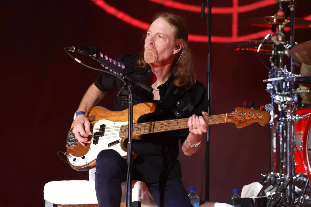 Foreigner tour dates 2026 bassist Jeff Pilson performing live with electric bass guitar.