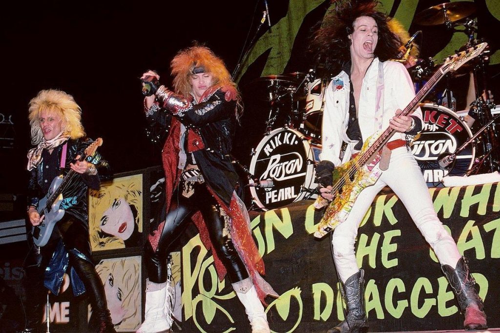 Poison performing live in full glam metal style, with big hair, flashy outfits, and high-energy stage presence.