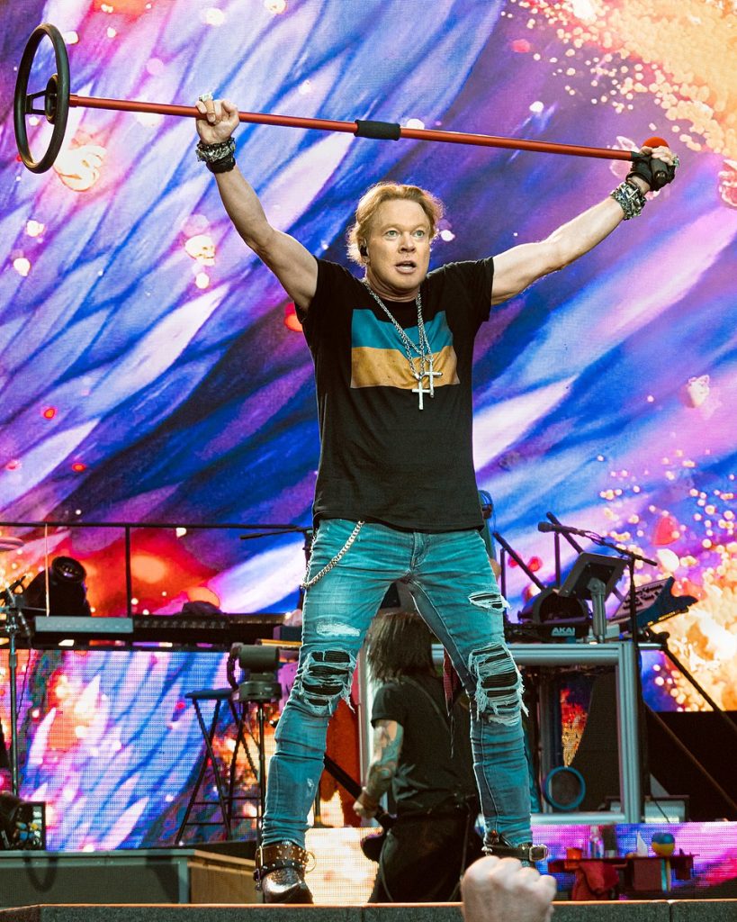 Axl Rose Live in London 2022 - Classic Rock Artists Guns N' Roses members: Axl Rose performing live on stage holding a microphone stand above his head during a concert in London 2022.