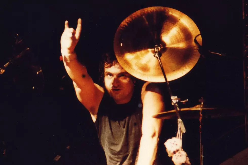 Vinny Appice Black Sabbath Live Performance Photo - Classic Rock Artists Vinny Appice Black Sabbath drummer performing live on stage throwing up rock horns with cymbals behind him during 1980s concert.