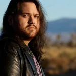 Wolfgang Van Halen refuses to compromise his artistic vision - portrait of the Mammoth frontman in leather jacket against desert landscape.