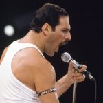 Freddie Mercury Live Performance - A Life in Lyrics 2026 - Classic Rock Artists Freddie Mercury performing live in white tank top holding microphone, featured in A Life in Lyrics book announcement.