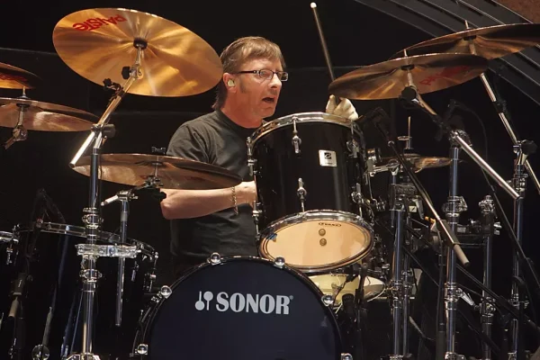 Phil Rudd AC/DC drummer performing behind black Sonor drum kit with Sabian cymbals.