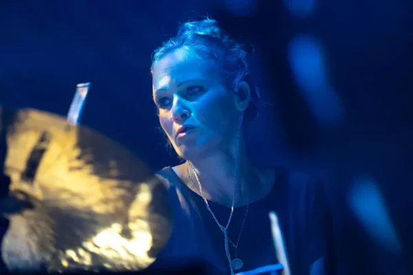 Rush's new drummer Anika Nilles performing live on stage with dramatic blue lighting and cymbals.