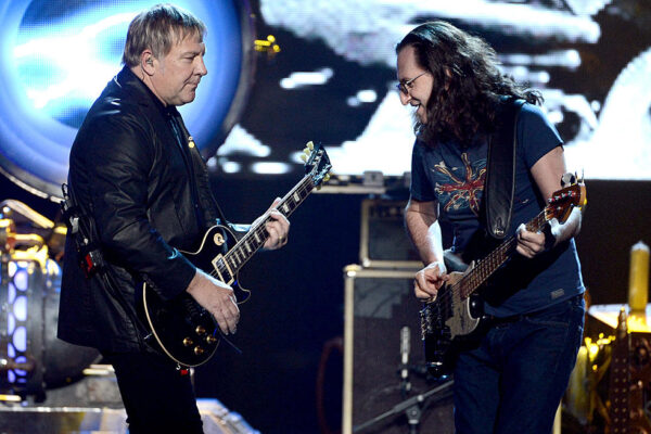 Alex Lifeson playing Gibson Les Paul guitar and Geddy Lee playing bass performing together on stage at Rush concert with blue stage lighting