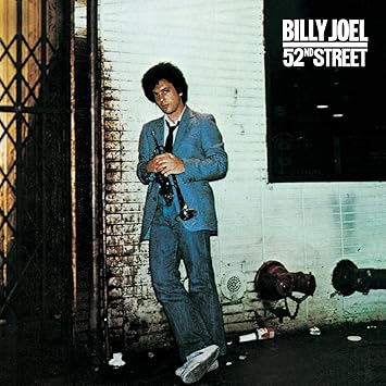 52nd Street by Billy Joel album cover 1978 showing Joel in blue suit against New York City street backdrop