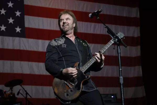 Don Barnes of 38 Special performing on stage during the 38 Special tour with an American flag backdrop