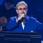 Elton John teases two new albums while performing at piano in signature blue suit and sunglasses