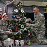 Two soldiers decorating office Christmas tree listening to rockin christmas songs during holiday season