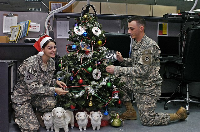 Two soldiers decorating office Christmas tree listening to rockin christmas songs during holiday season