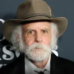 Grateful Dead Bob Weir wearing a brown hat and black suit at an event