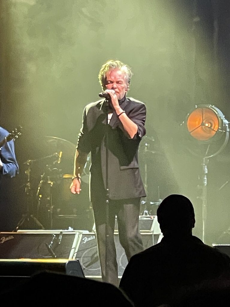 John Mellencamp performing live on stage in San Francisco in 2023, singing classic John Mellencamp songs during a concert appearance.