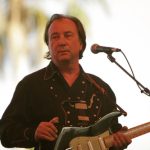 Jim Messina performing live on stage with his signature green electric guitar during his 2026 retrospective tour.