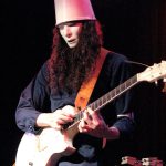 Buckethead performing live with Guns N' Roses wearing his signature KFC bucket and white mask