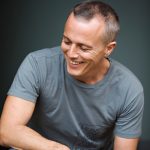 Curt Smith smiling in a casual portrait, the Tears for Fears singer and bassist photographed in a relaxed moment.