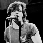John Mellencamp performing live on stage with guitar