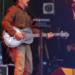 Les Claypool performing live with his custom bass, the defining image of a four-decade career