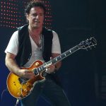 Neal Schon performing live with his guitar on stage
