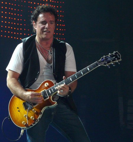 Neal Schon performing live with his guitar on stage
