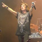 Joe Lynn Turner performing live on stage during a Rainbow concert, holding a microphone and pointing to the crowd.