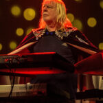 Rick Wakeman playing keyboards on stage in a sequined cape