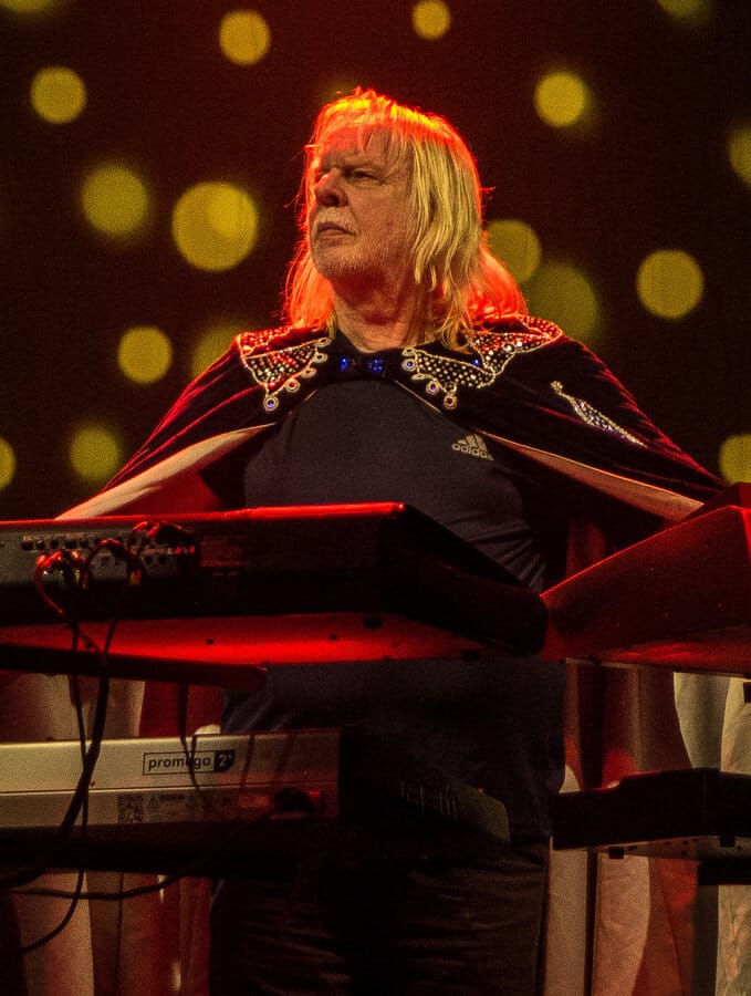 Rick Wakeman playing keyboards on stage in a sequined cape